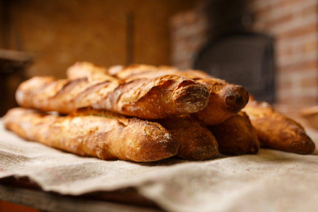 Warm, freshly baked rustic baguette stacked in a cozy bakery setting.