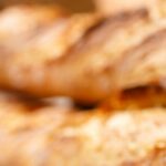 Warm, freshly baked rustic baguettes stacked in a cozy bakery setting.