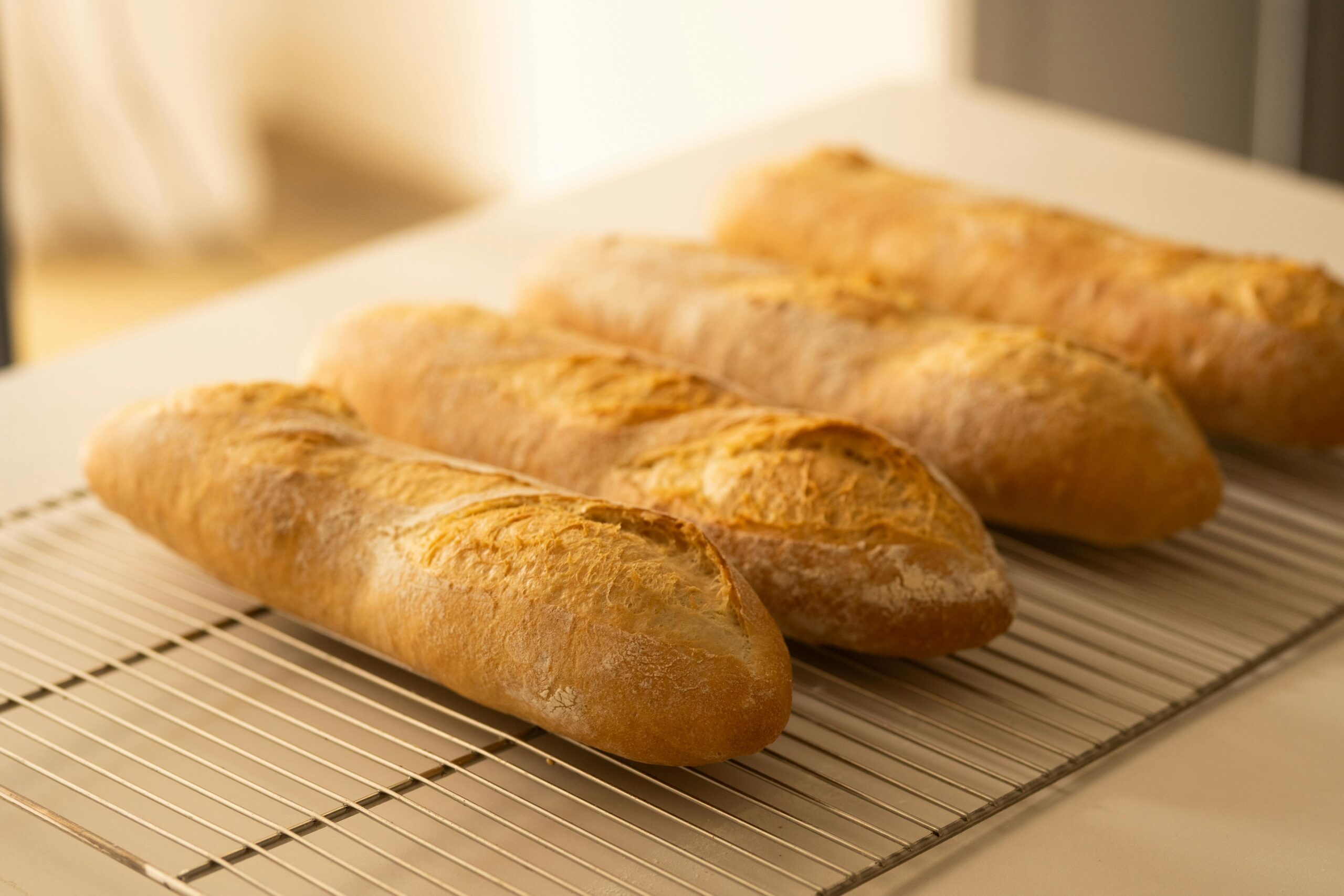 Golden homemade baguettes cooling on a rack, capturing the essence of artisanal baking with a warm and inviting tone.