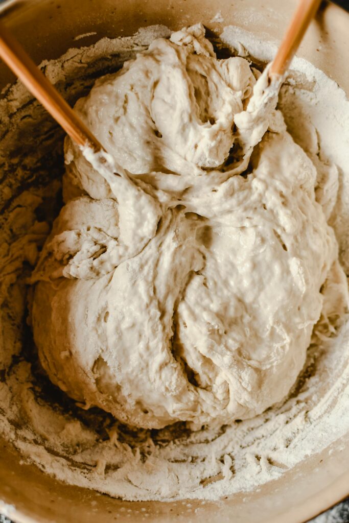 pexels-photo-7235886-7235886 Close-up of raw bread dough being mixed with chopsticks in a bowl for a rustic baking experience.